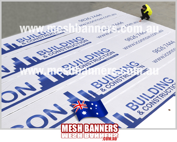 Man in safety vest inspecting builders construction mesh banner signs