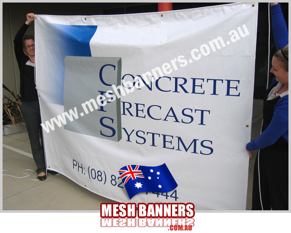 Girls from the art department holding up a temporary fence banner sign